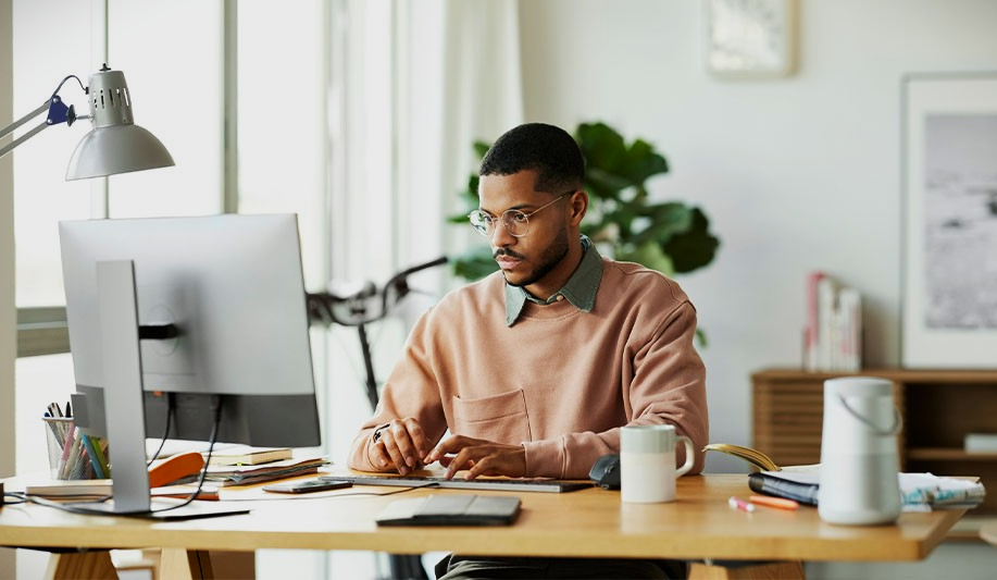 Homem sentado em uma mesa usando o computador